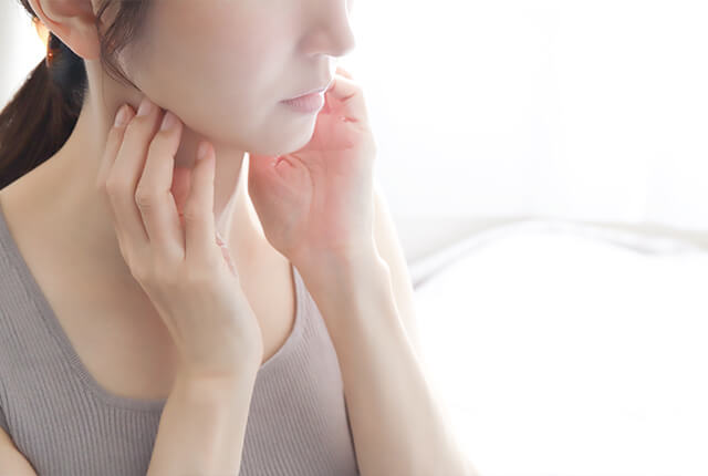 のどに両手を当てる女性